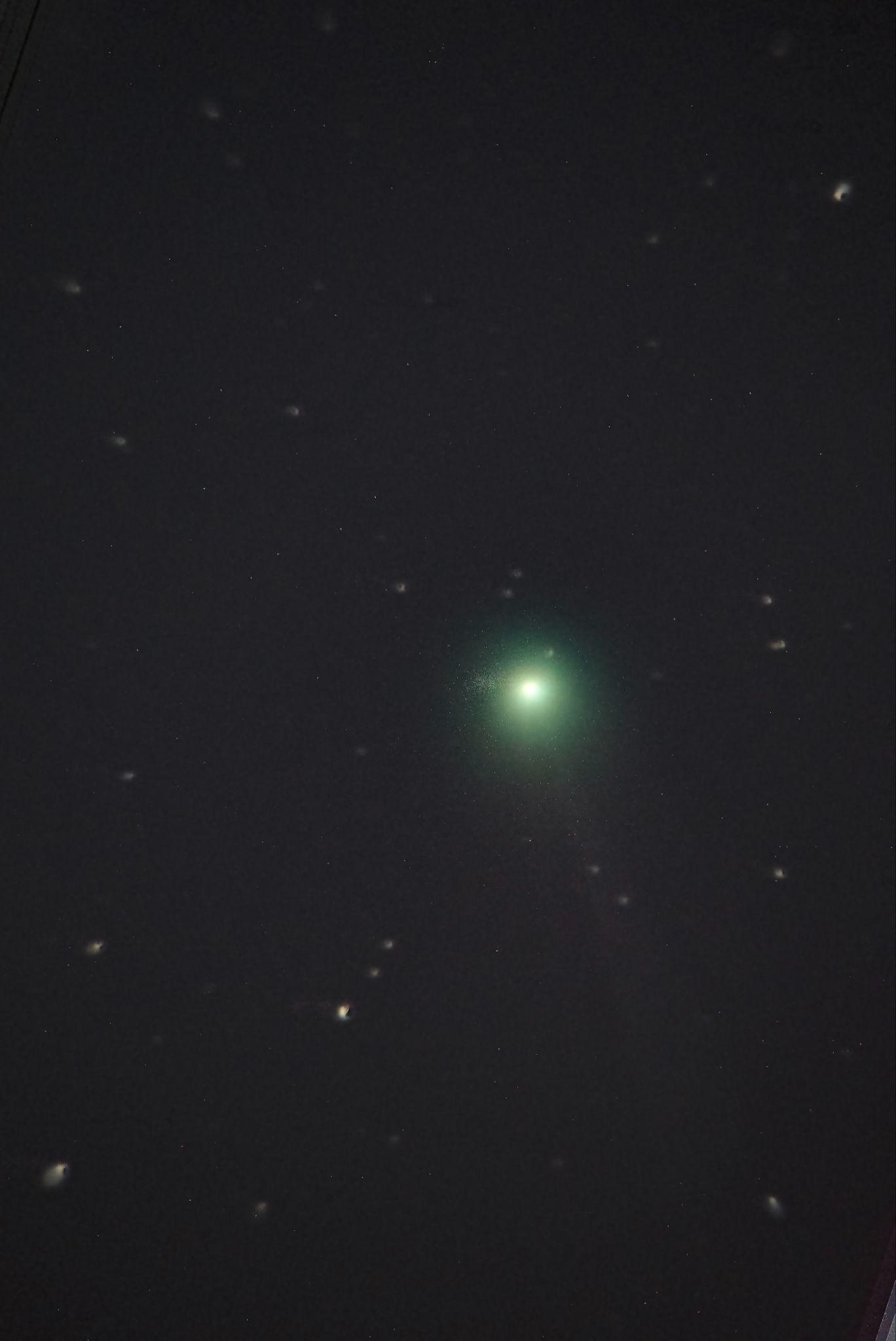 A green comet with a faint tail against a star field