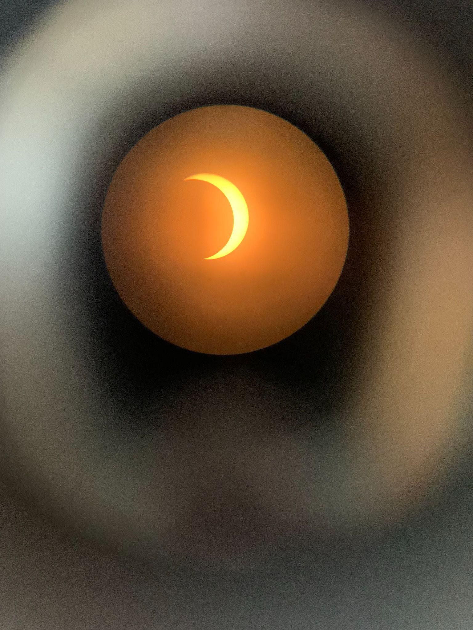 A crescent sun seen through a telescope eyepiece during a partial eclipse