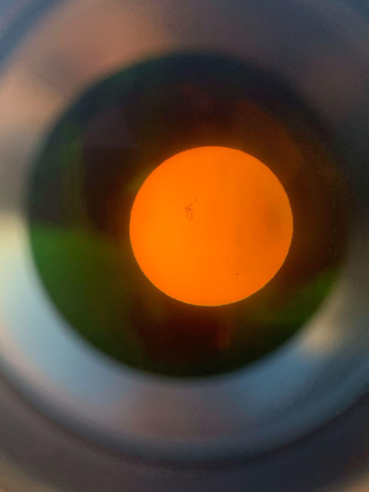 The sun seen through a filtered telescope eyepiece, with sunspots visible