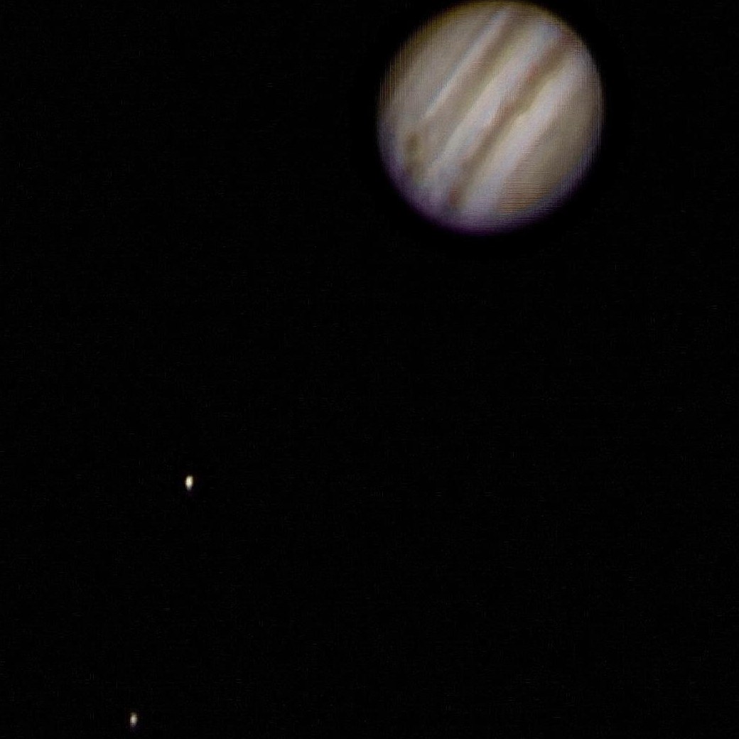 Jupiter with cloud bands and two of its moons