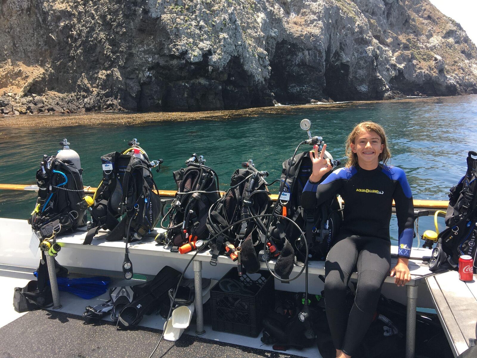 Adam sitting on a dive boat in the Channel Islands, scuba gear rigged along the rail behind him